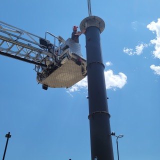 A Pacific Crematory technician working from a boom lift on a crematory stack.